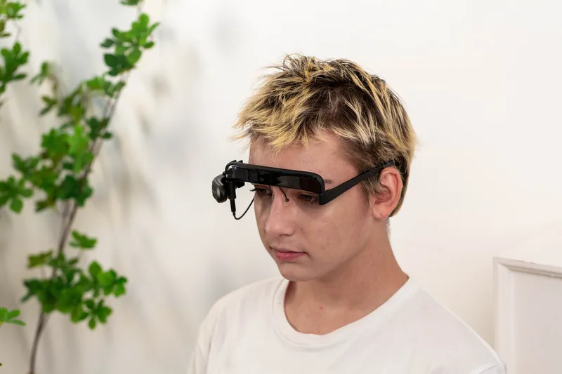 Person wearing GlassOuse Blink Switch eye-tracking headset for hands-free computer control